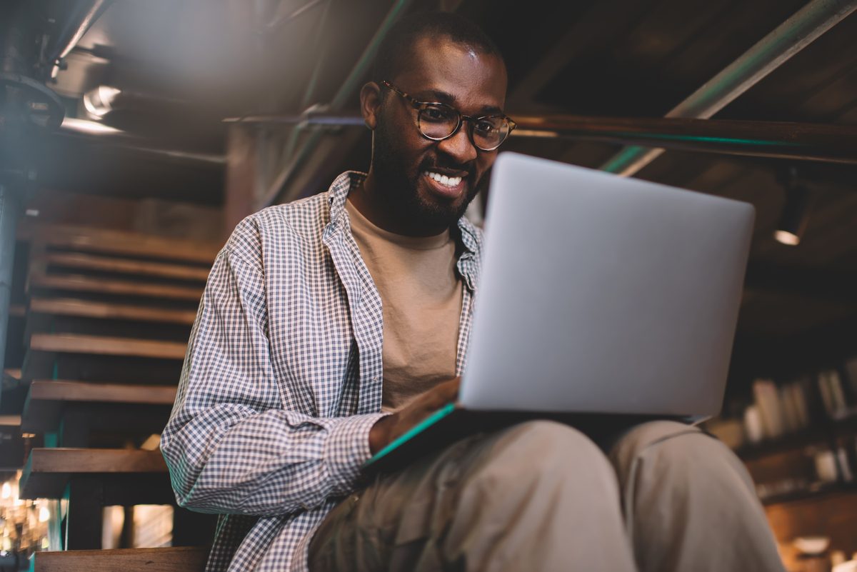 man with glasses smiling looking at his laptop