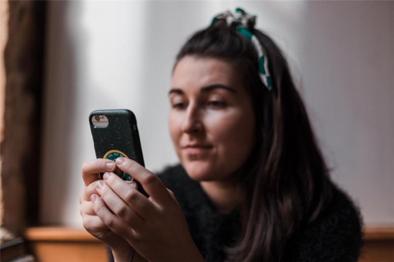 woman holding a smartphone, looking at it thoughtfully