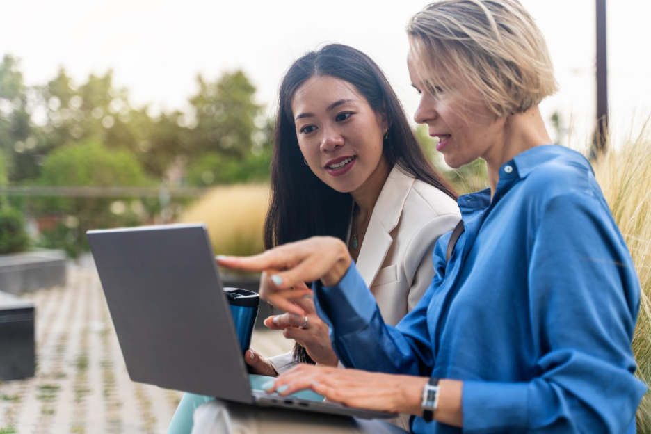 two women talking and pointing at a laptop